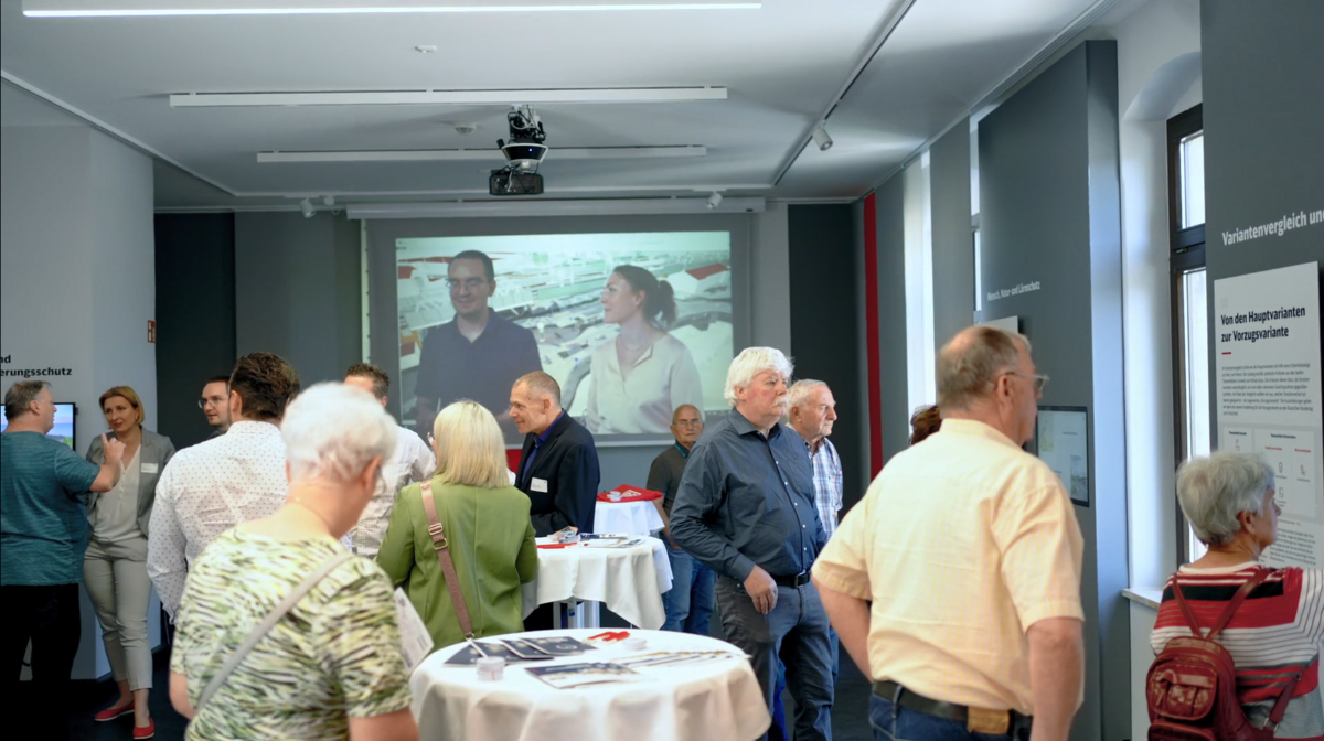 Well-attended room in the Heidenau information centre, where several visitors interact with each other and with the information material on display.