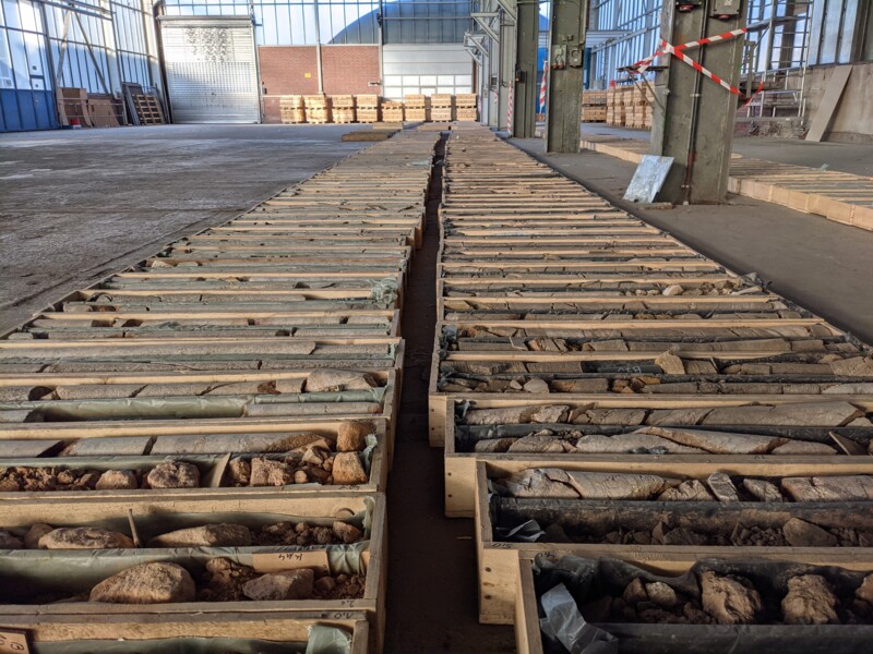 Many core drillings lay in two rows next to each other, each in a wooden basket. 